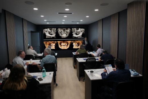 Dentists in the OsseoPure classroom reviewing a full-arch case on the CBCT wall.