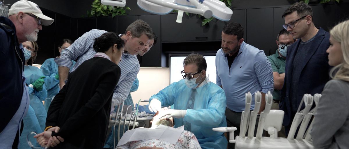 Dentists gathered around the chair watching Dr. Lasorsa during live surgery.